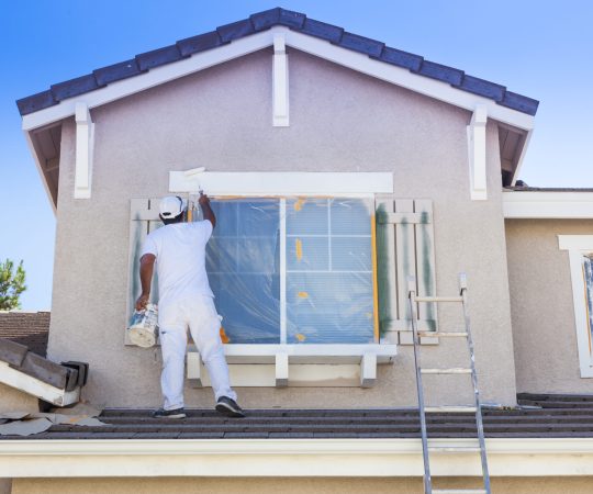 Busy House Painter Painting the Trim And Shutters of A Home.